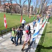 Students walk along sidewalk lined with international flags during the Conference on World Affairs