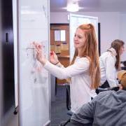 Student writes on a white board in the classroom