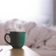 Hot cup of a coffee on a bedside table